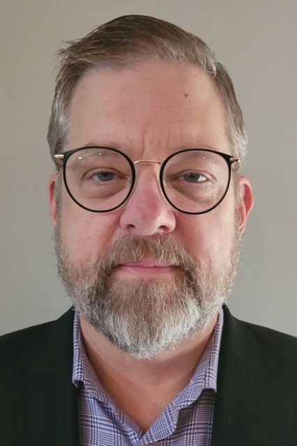 Headshot of ICBA Director of Education Kevin Leitner in a suit jacket and wearing round eyeglasses.